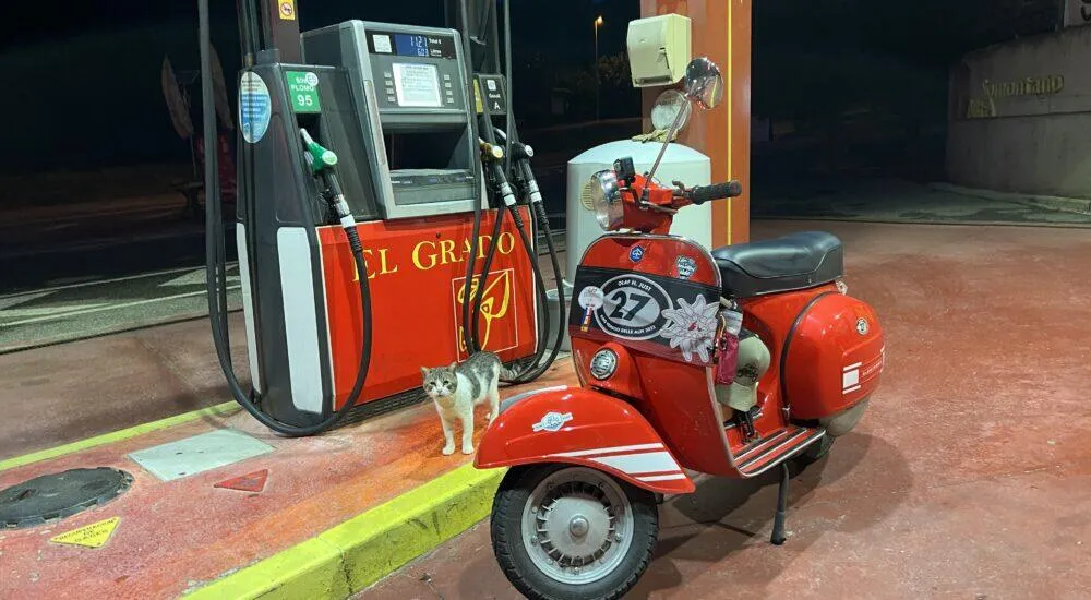 Rote Vespa Rally steht neben der Tanksäule mit dem Text El Grato