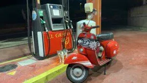 Rote Vespa Rally steht neben der Tanksäule mit dem Text El Grato