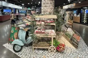 Vespa VNB125 steht zwischen Ständen mit Salami und Käse im Migros Winterthur 11-2024
